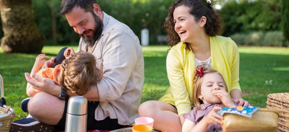 Happy family having a picnic on a sunny day in a park, enjoying togetherness and relaxation.