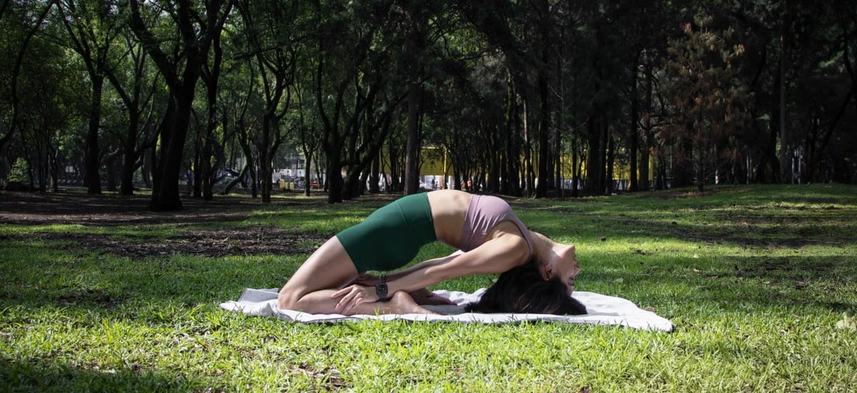 Woman performing a yoga pose on a sunny day in a lush green park in Ciudad de México.