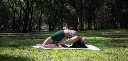 Woman performing a yoga pose on a sunny day in a lush green park in Ciudad de México.